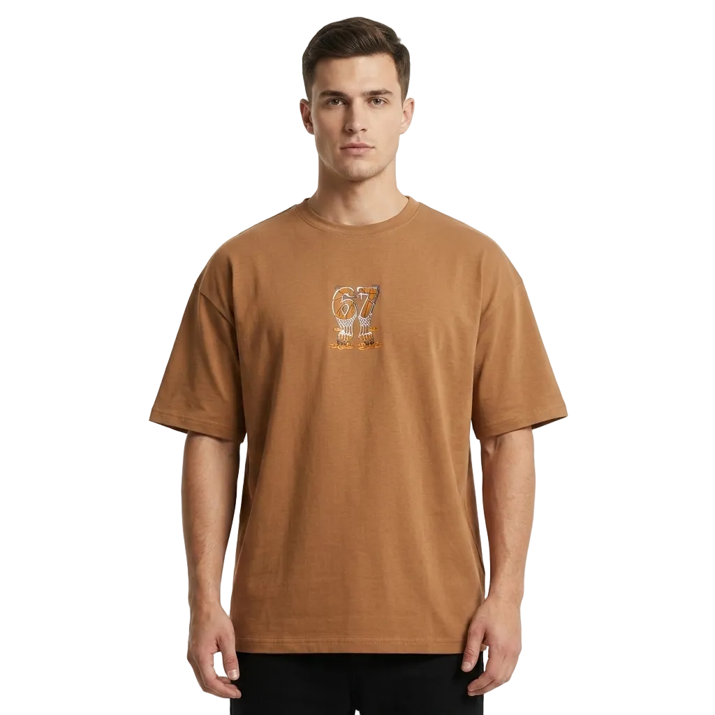 A man wearing a brown short-sleeve t-shirt with a small graphic on the left chest, standing against a light gray background.