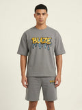 Man wearing a gray t-shirt with 'BLAZE' logo and matching shorts on a beige background