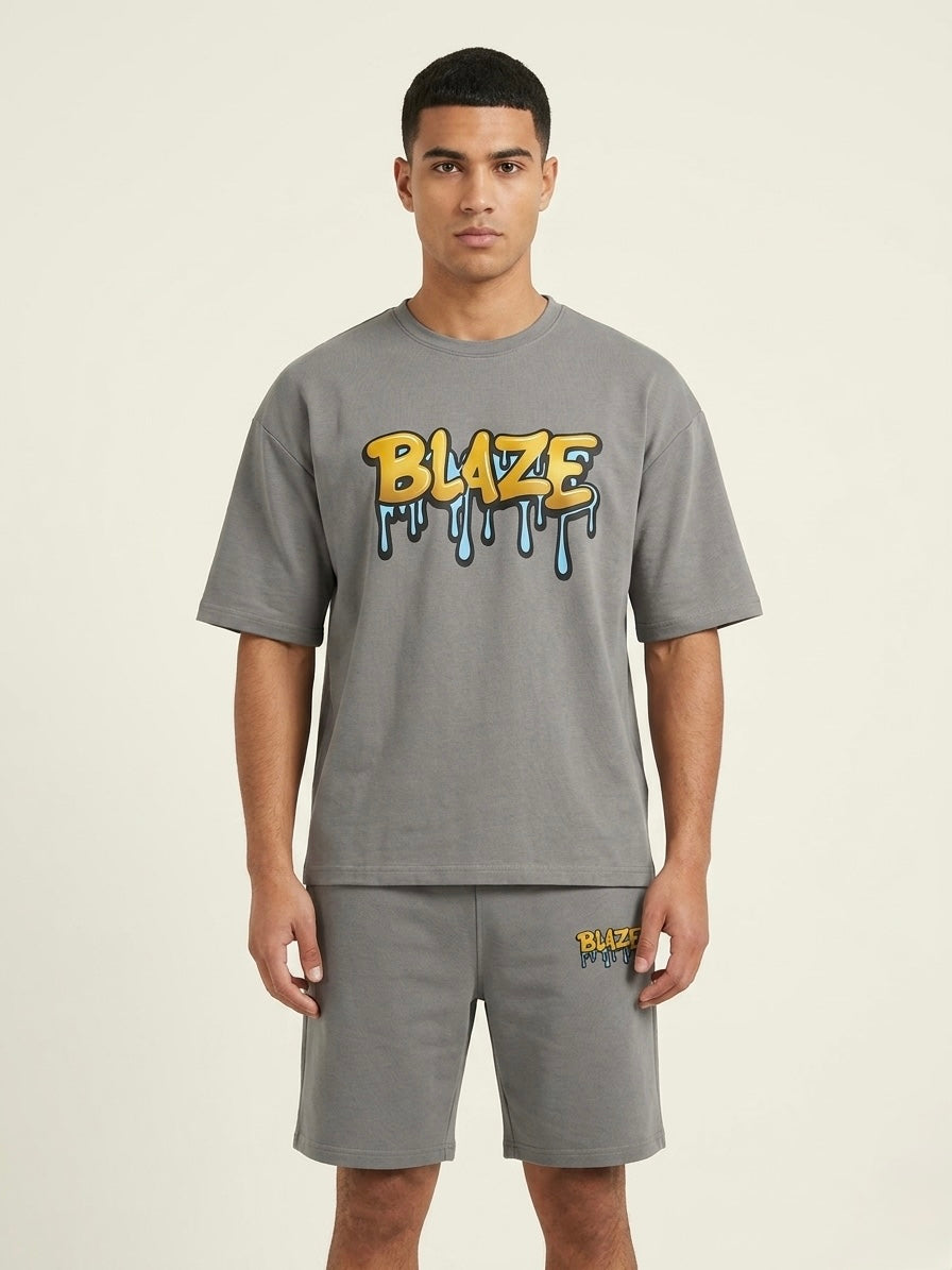 Man wearing a gray t-shirt with 'BLAZE' logo and matching shorts on a beige background